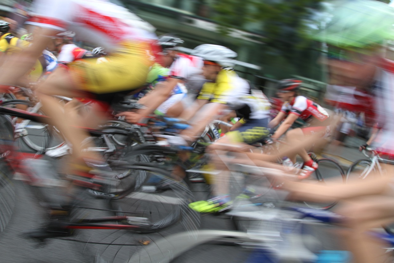 Das Bild zeigt Prifi-Radrennfahrende, die mit hoher Geschwindigkeit von Rechts nach Links fahren. Die Radfahrenden sind leicht verwischt.