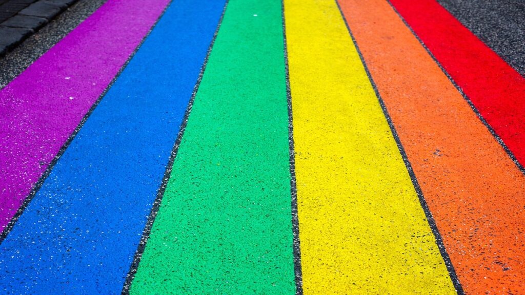 Das Foto zeigt einen Zebrastreifen in den Farben der Regenbogenfahne.